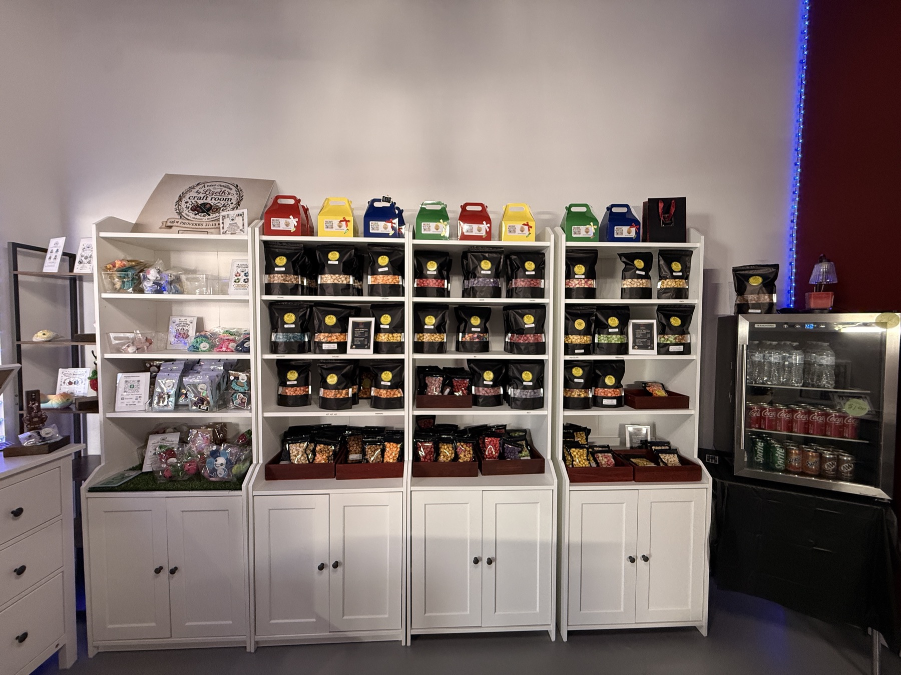 Full shelf display of Ike's Gourmet Popcorn bags organized by flavor, with gift boxes on top, at the Weslaco, TX shop